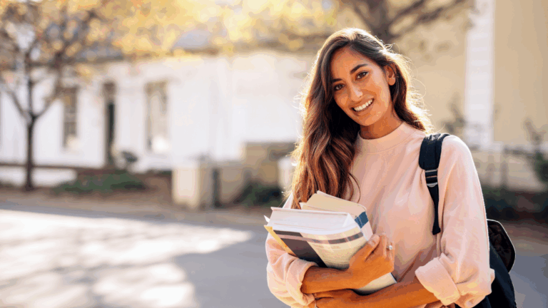 Strategic Extracurriculars image if female law student on campus smiling and holding textbooks