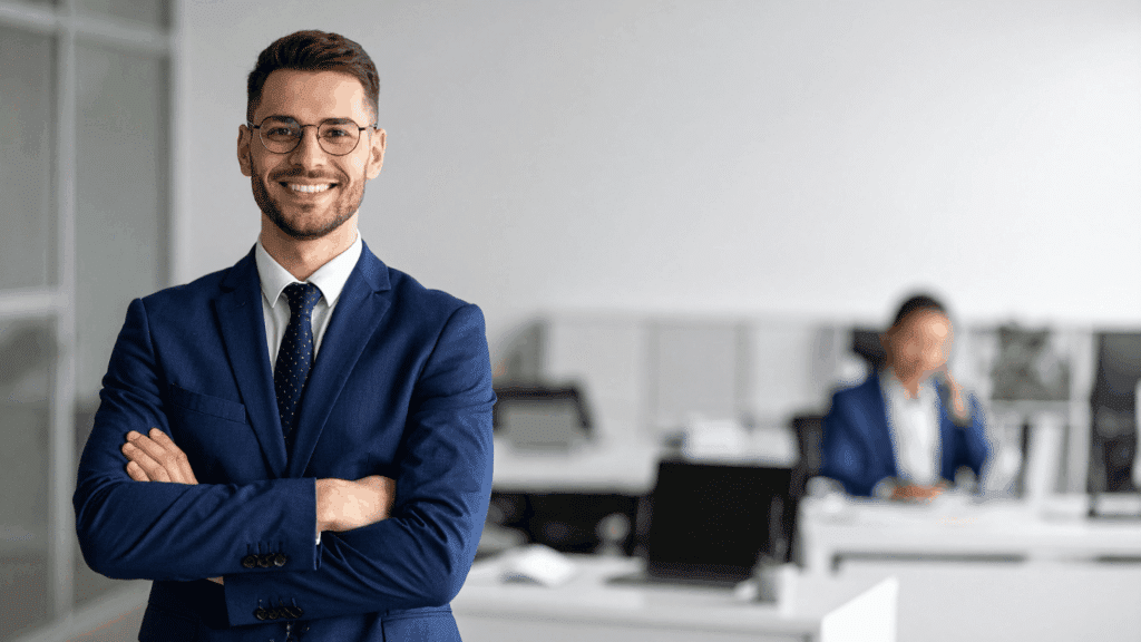 Young male adult business professional wearing a suit and smiling in career office setting.