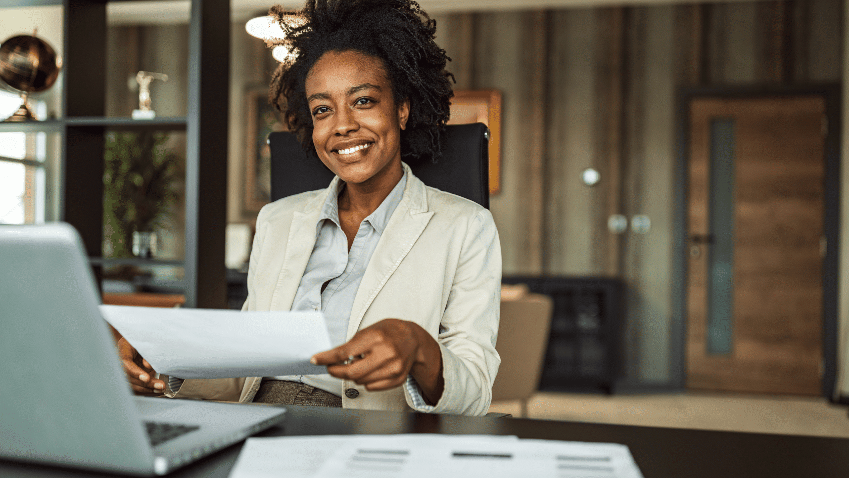 Young business professional woman at desk with laptop smiling