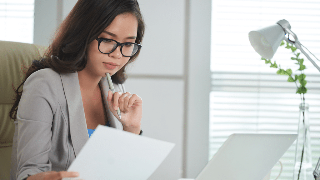 Young business professional woman at desk with laptop and documents