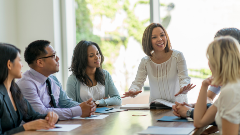 Group of business professional dressed adults at conference room table discussing mediation details